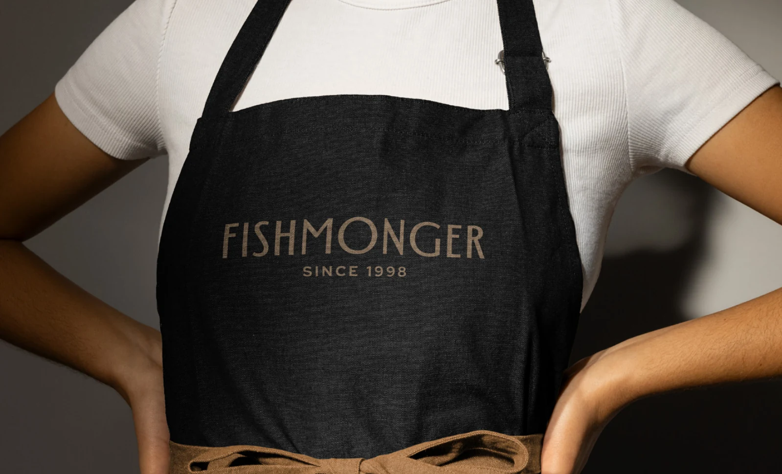 The Fishmonger identity on a dark apron