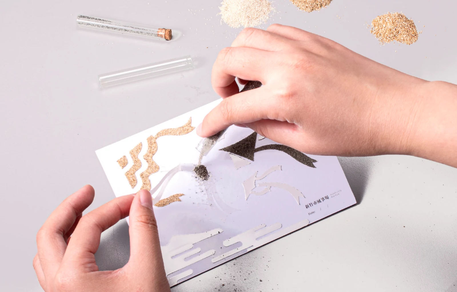 Applying coloured sand to a postcard